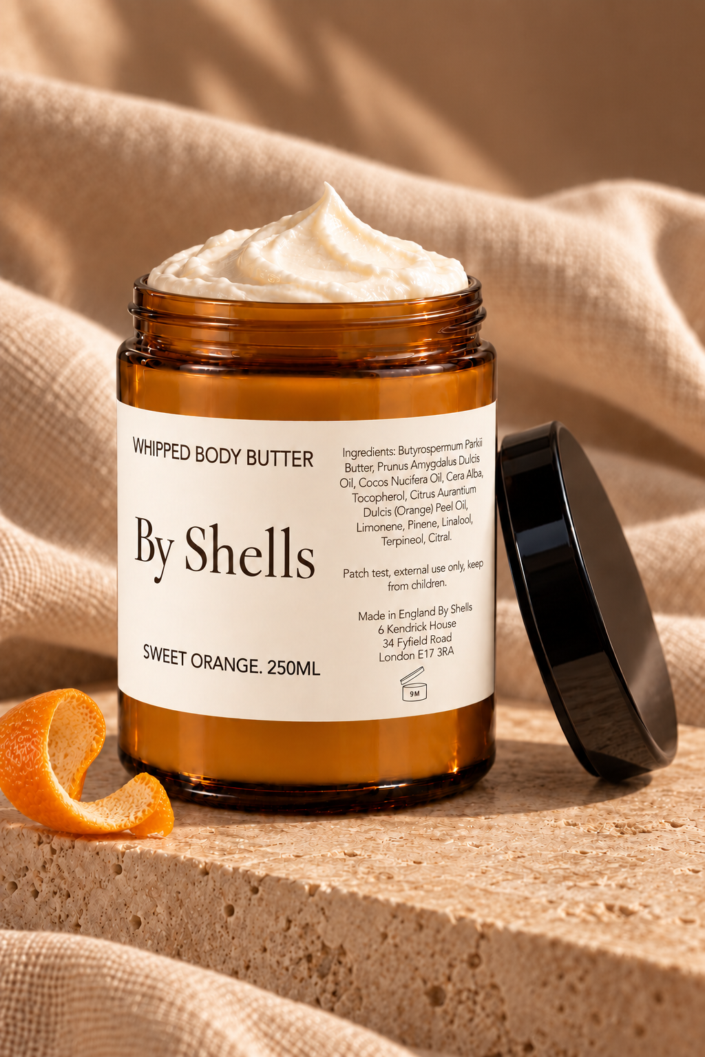By Shells Sweet Orange whipped body butter, 250ml amber glass jar with the lid off and orange peel beside it